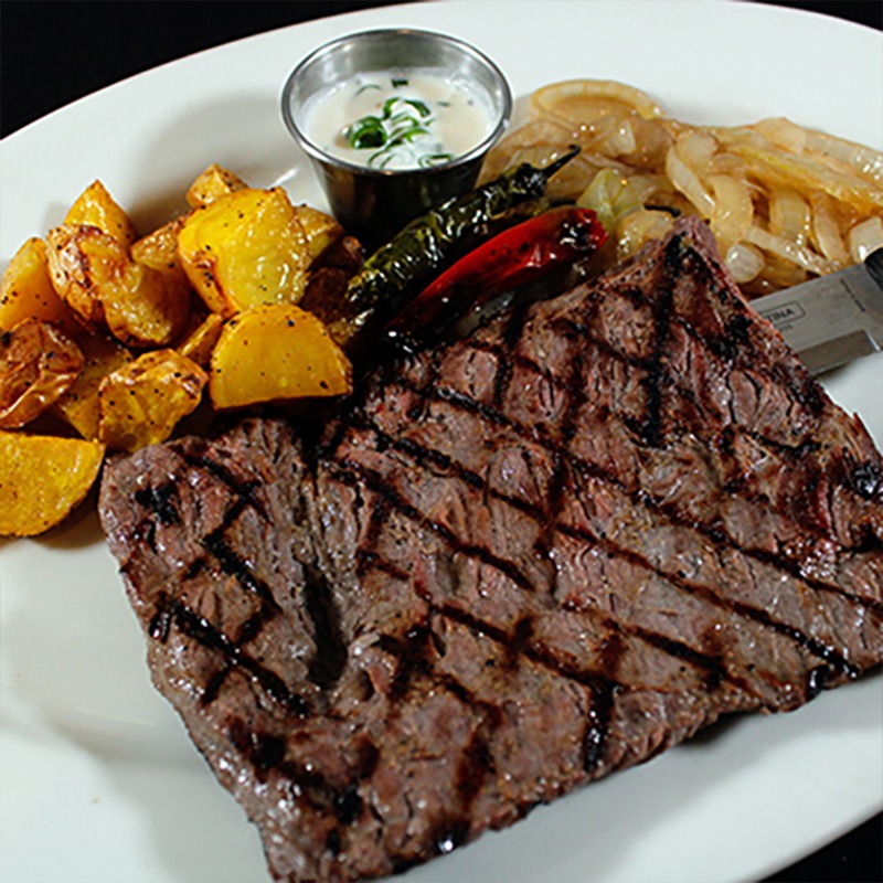 Corte de carne servido en plato de restaurante con guarnición de papas